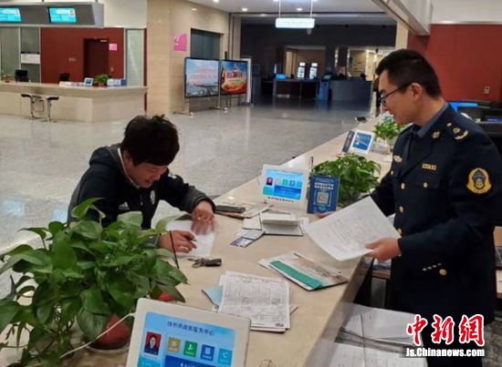 徐州市行政审批中心交通窗口工作人员指导船民填报“船舶营运一件事”申请表格。