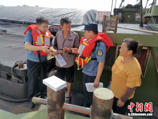 淮阴船闸工作人员走上船头，向船员宣传《苏北运河船舶过闸诚信管理办法》。