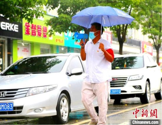 雨中王德亮用小喇叭宣传防疫知识。 郝婷婷 摄 雨中王德亮用小喇叭宣传防疫知识。 郝婷婷 摄