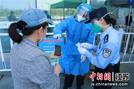 民警在徐州東站進站口幫助工作人員對旅客進行防疫按規定。 閆銘 攝
