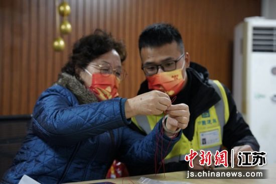 社区居民与工地工人一起编制中国结。 刘贤邦 摄 社区居民与工地工人一起编制中国结。 刘贤邦 摄